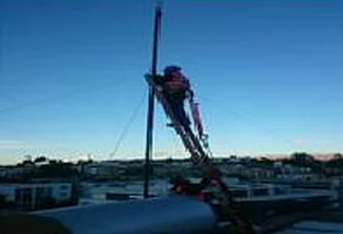 Técnico trabajando en un mástil al atardecer